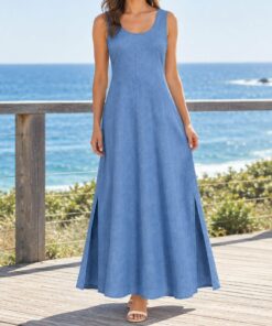 Woman wearing a chambray blue linen maxi dress walking along the shoreline, shown from the shoulders down
