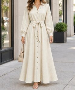 Woman in a cream boho shirt dress with rolled sleeves walking down a city street, shown from the neck down