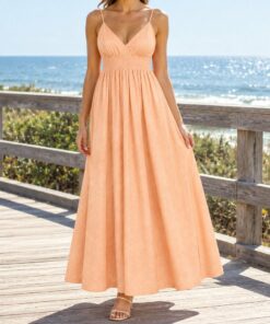 Woman wearing a peach maxi sundress on a sunny beach boardwalk, framed from the neck down