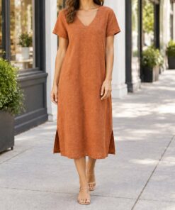 Woman in a terracotta V-neck tunic dress walking through a city square, shown from the neck down