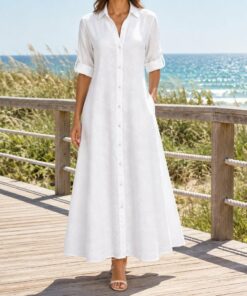 Woman wearing a white maxi shirt dress open over a swimsuit on the beach, framed from the neck down